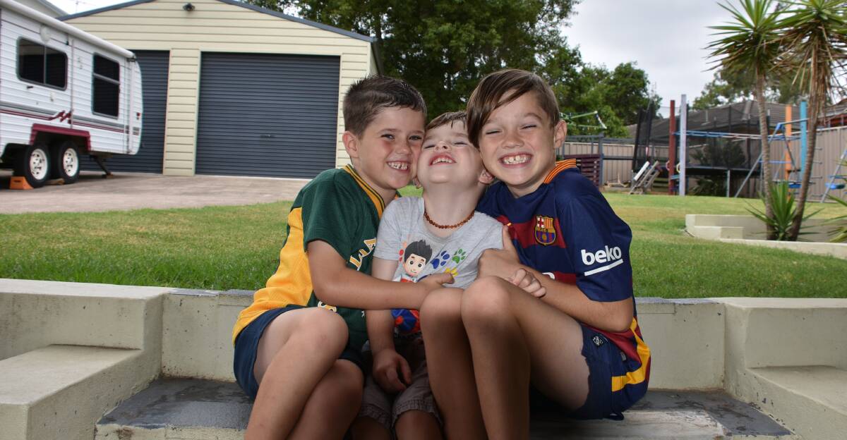 Brotherly love: Riley, Sebastian and Preston Stace share a hug at their East Maitland home. Picture: Lachlan Leeming. 
