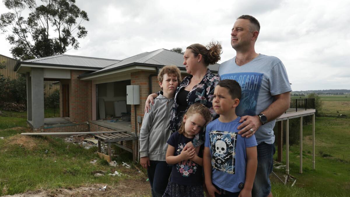 DETERMINED: Phillip Kapeller and Rachael Cesnik outside their incomplete Gillieston Heights home in September last year with children Loui, 11, Zeke, 9 and Violet 6. The couple want action taken against the builder. Picture: Simone De Peak