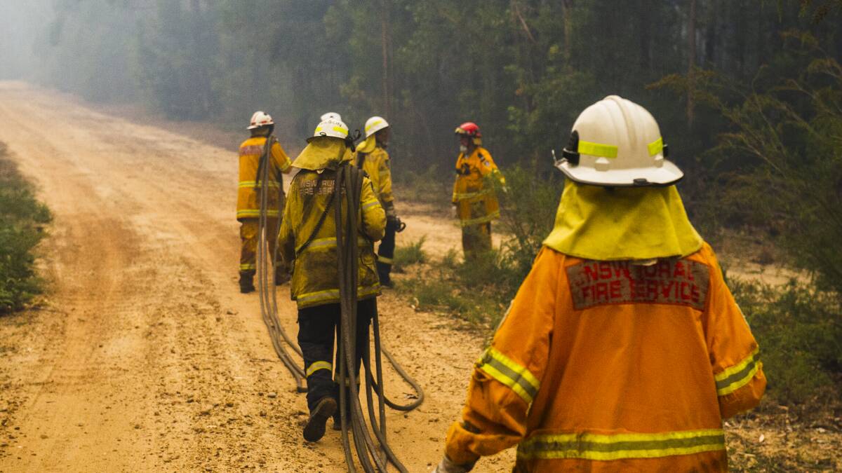 NSW Rural Fire Service firefighters work to protect a property on Tallow Wood Rd from the Currowan fire. Picture: Dion Georgopoulos