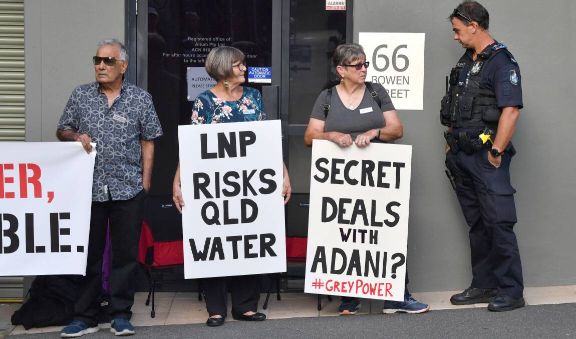 Beyond politics: Anti-Adani coal mine protesters next to a police officer outside the Queensland Liberal National Party headquarters in Brisbane on Thursday, April 11. Photo: AAP 