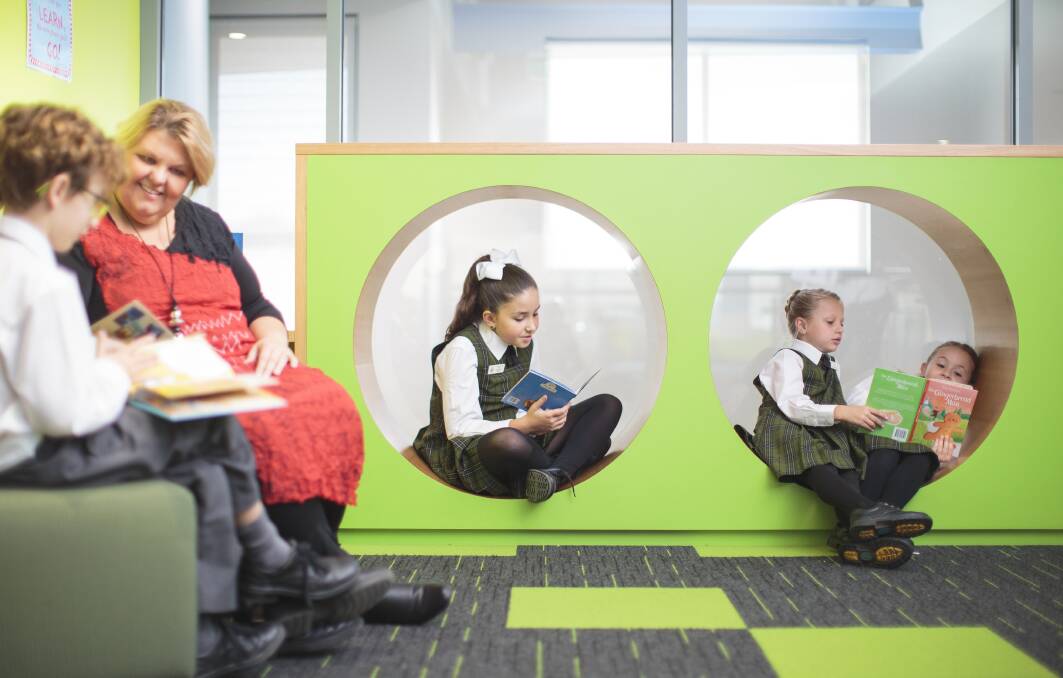 Mrs Margaret Pond, Head of the Junior School at St Philips, listens to students read in the brightly coloured pods available around the school.