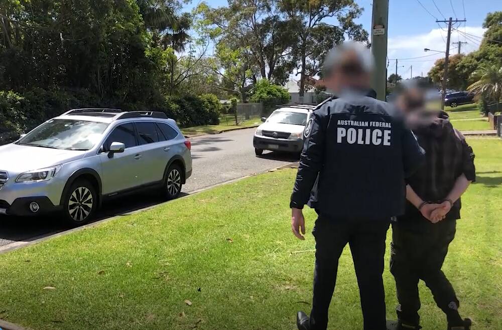 ARREST: The 22-year-old man charged with downloading and transmitting child abuse material being led away from his Charlestown home by an Australian Federal Police officer last week. 