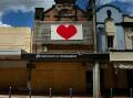 A bright red heart banner attched to the second story of the boarded up Newcastle Permanent buliding in Lismore. Picture: Marina Neil