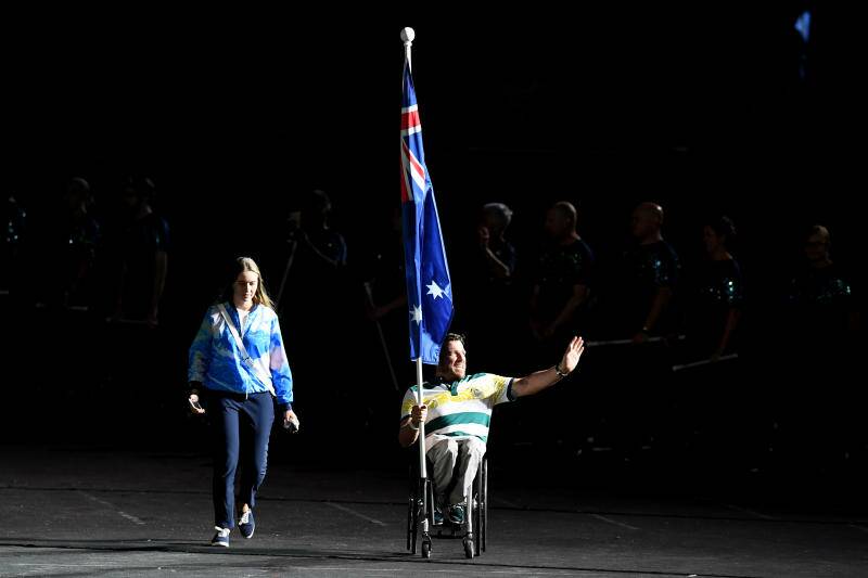 Kurt Fearnley carries the Australian Flag during the the closing ceremony of the XXI Commonwealth Games on the Gold Coast, Australia. Photo: AAP.