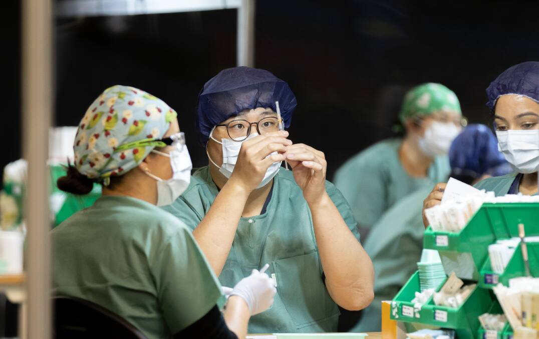 Staff prepare shots at government COVID vaccination clinic. Picture: Sitthixay Ditthavong