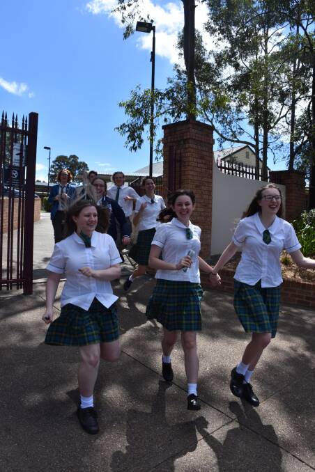 OUT OF THE GATES: Hunter Valley Grammar's Molly Johnson, Ellie West and Elsie Leask with other drama students following their final HSC exam on Tuesday.