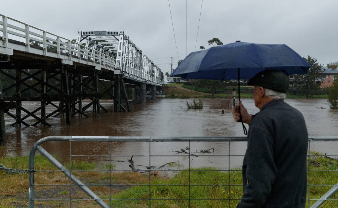John Wright looks at the rising Hunter River flowing under the Morpeth Bridge. Picture: Max Mason-Hubers 