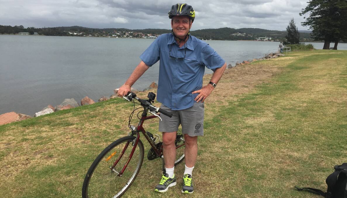HALFWAY: Scott Bevan and his trusty bicycle on the foreshore near Speers Point during his epic pedalling commute to work in Newcastle. 
