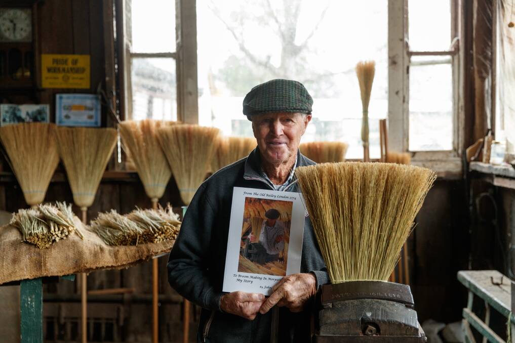 SWEEP OF HISTORY: John Wright, in his renowned broom-making shed, holding the book he's written.