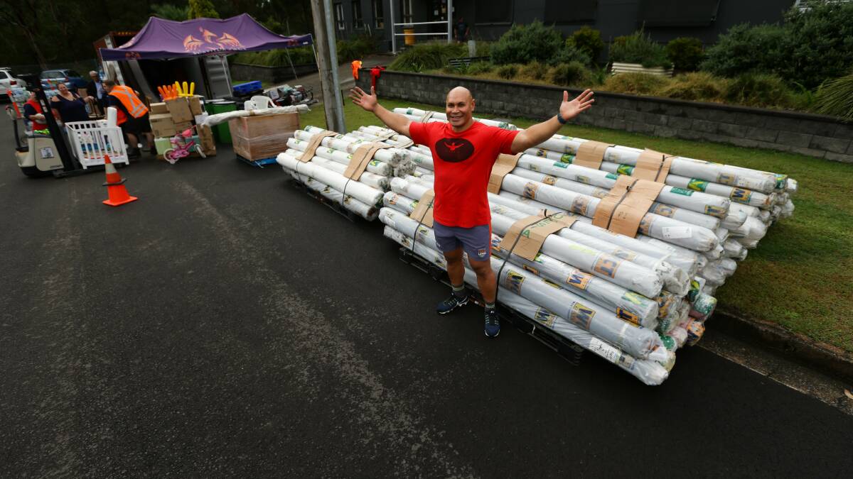 Sione Finefeuiaki with rolls of outdoor fabric donated by Rutherford firm Wax Convertors Textiles Australia.