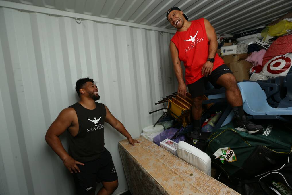 Phil Bradford, from the Hunter Wildfires rugby team, and Carl Manu, from Newcastle Pasifika, help pack the container. Picture: Jonathan Carroll 