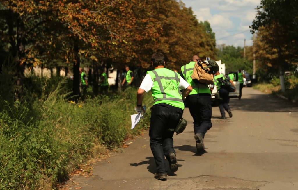 Members of the international MH17 recovery team run for cover as gunfire breaks out in the streets of Rassypnoe, the so called Cockpit village, forcing  the MH17 recovery team to abandon its last spot search, which was to be at the actual cockpit site. Rassypnoe. Photo: Kate Geraghty