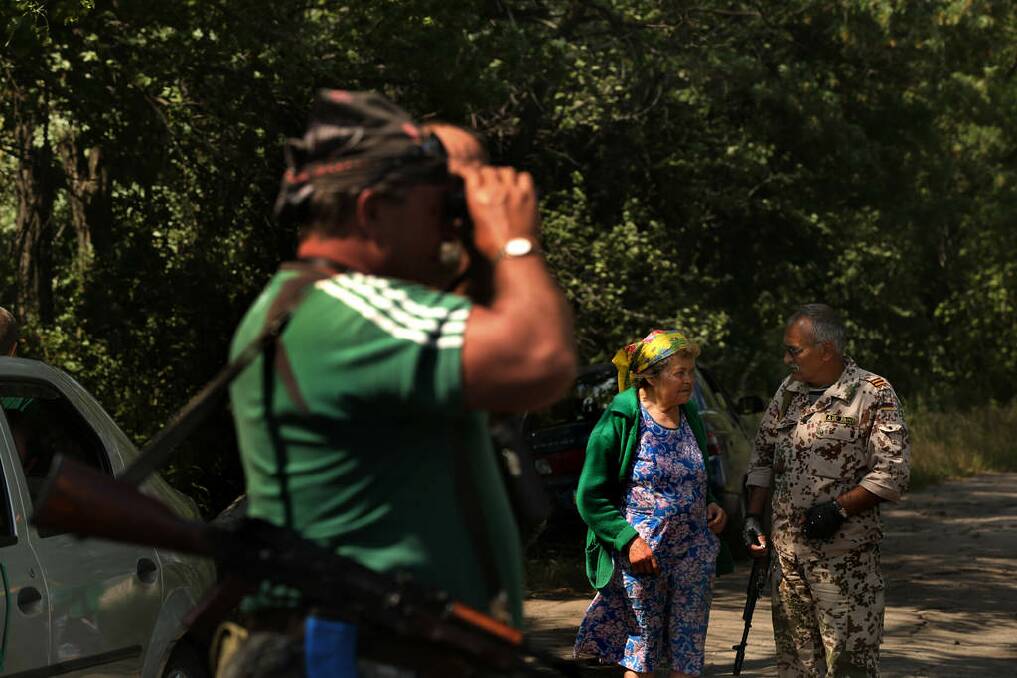 Pro Russian rebels scan the area near the MH17 crash site and talk with locals who are trapped due to fighting in the area surrounding the crash site today.  This particular group of rebels escort the OSCE and Australian and Dutch police to and from the MH17 crash site.. Photo: Kate Geraghty