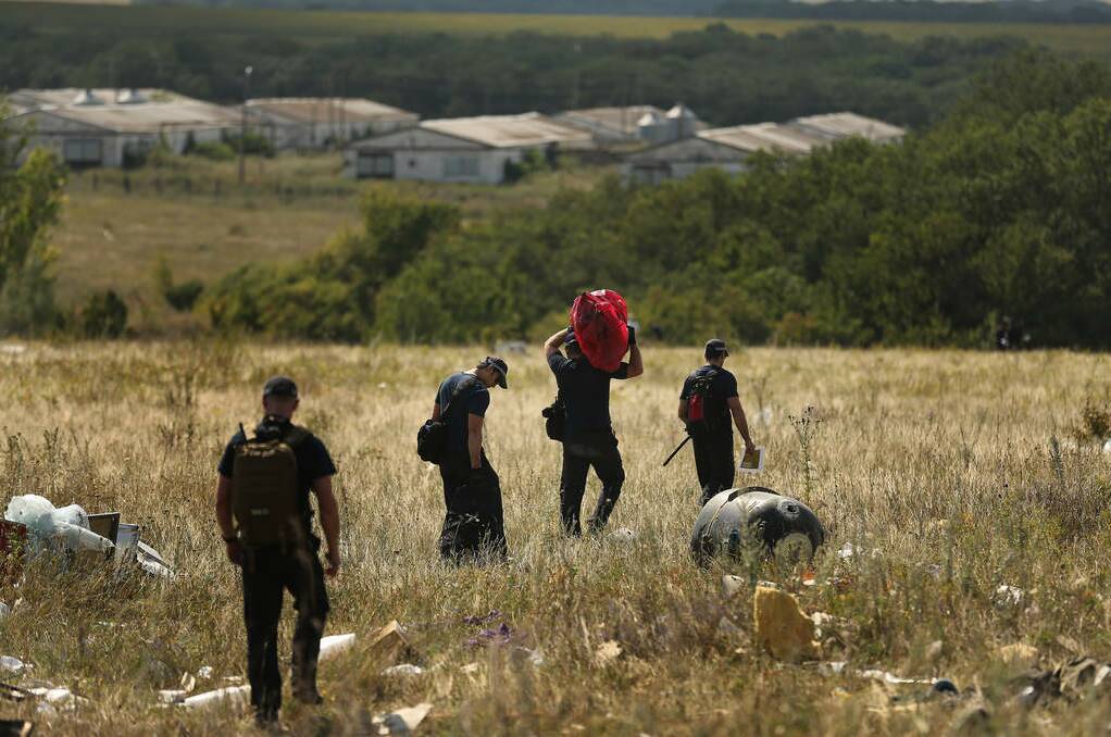 Australian Federal Police officers carry victims personal belongings from the MH17 crash site in the fields outside the village of Grabovka. Photo: Kate Geraghty
