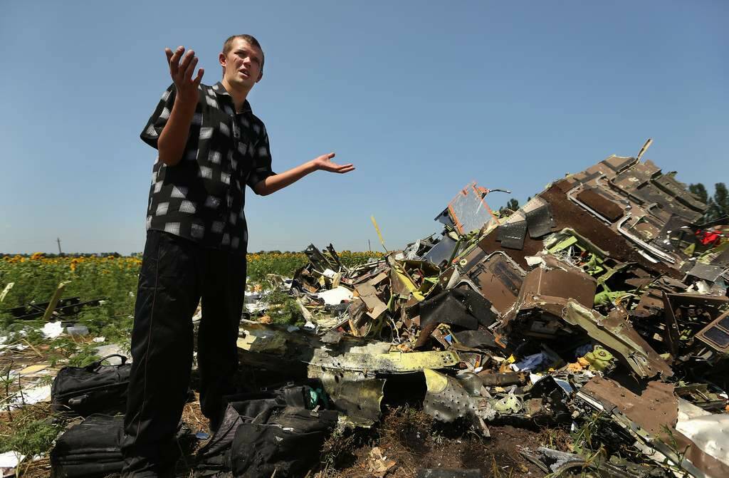 Donetsk People's Republic sniper Eugene Lukovkin aged 30 stands amongst the pilots bags at one of the sites where he witnessed the front section of Malaysian flight MH17 crashing and found the pilots bodies, on the outskirts of Rassypnoe village. Photo: Kate Geraghty