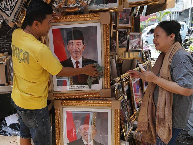 A worker cleans a portrait of Indonesian President Joko Widodo who will begin a new term on Sunday.