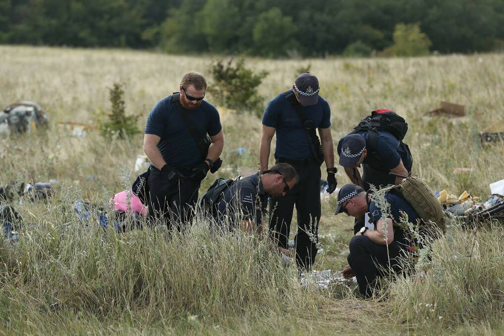 Australian Federal Police officers and their Dutch coutnerparts collect human remains from the MH17 crash site in the fields outside the village of Grabovka. Photo: Kate Geraghty