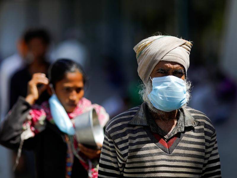 People wearing protective masks queue for food during India's 21-day nationwide lockdown.