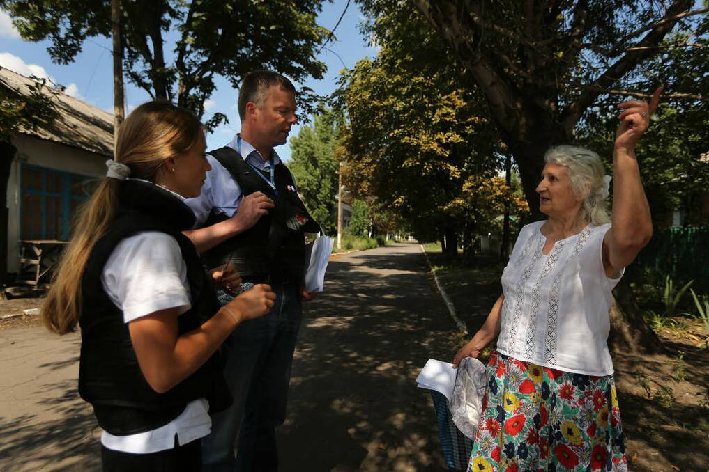 Deputy head of the OSCE mission Alexander Hug (2nd from right) talks with retired kindergarten teacher Era Pavlovna 76 (right) after handing her a phamphlet giving information on how to return debris and personal belongings of the victims of MH17 crash, in Rassypnoe. Photo: Kate Geraghty