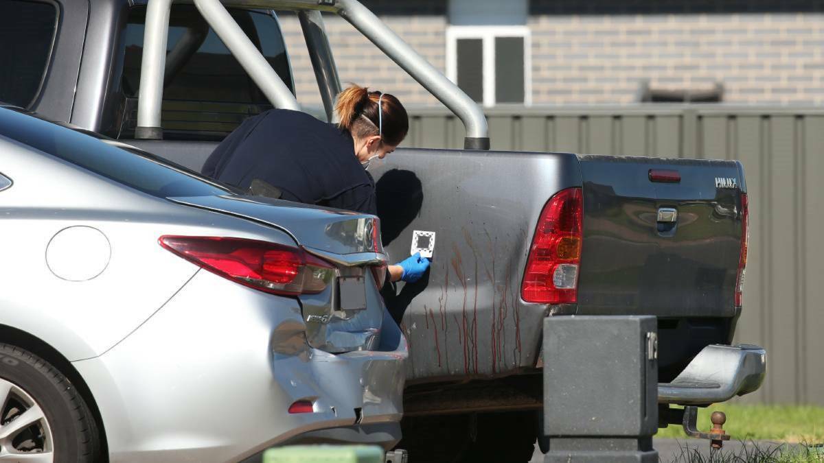 INVESTIGATION: Crime scene officers examine blood splatter on a vehicle outside the property at Cliftleigh in March last year. Father and son Tony and Bradley Maybury pleaded not guilty on Wednesday. 