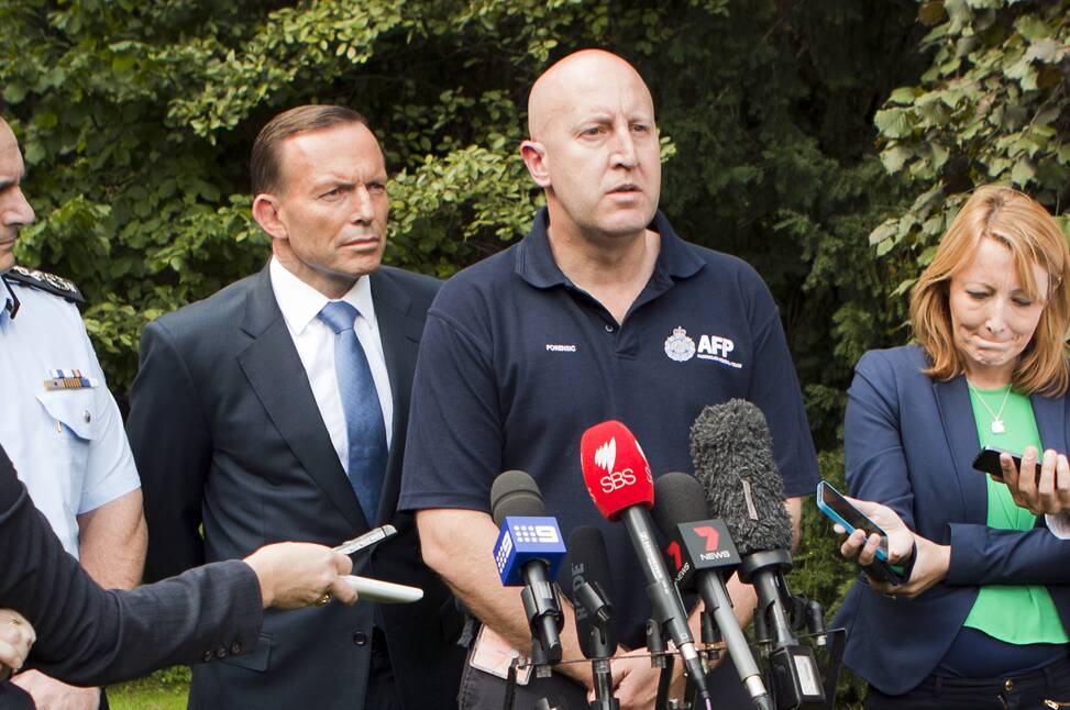 Dr Simon Walsh (navy polo shirt) was the Australian Federal Police chief scientist working in disaster victim identification following the downing of the MH17. He is pictured with the then Australian Prime Minister Tony Abbott. Picture by AFP