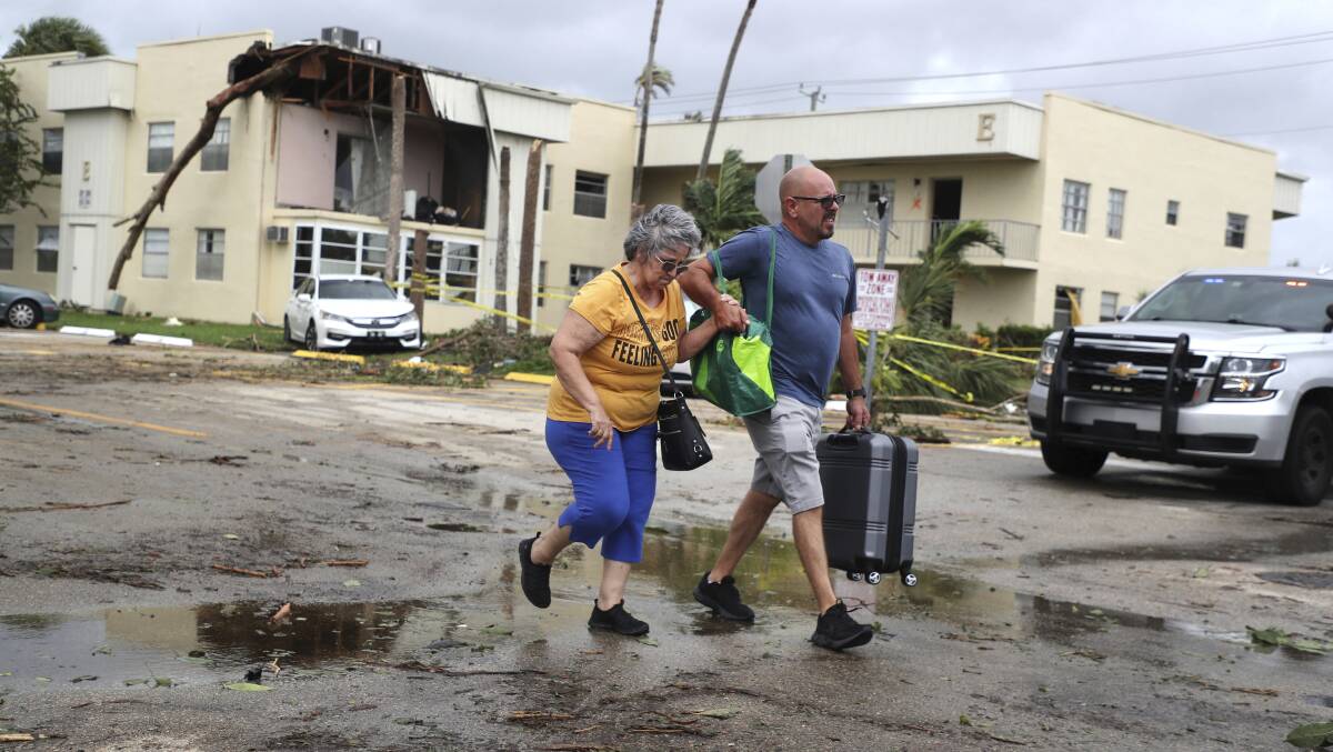 King Point resident Maria Esturilho is escorted by her son Tony Esturilho as they leave behind the damage from an apparent overnight tornado spawned from Hurricane Ian at Kings Point 55+ community in Delray Beach. Picture by Carline Jean /South Florida Sun-Sentinel via AP