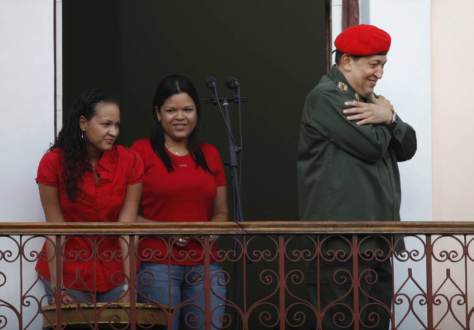 Venezuela's President Hugo Chavez greets supporters while appearing with his daughters Rosa (L) and Maria on a balcony of Miraflores Palace soon after his return to the country from Cuba, where he underwent surgery and treatment for cancer, in Caracas in July, 2011. Photo:  REUTERS/Carlos Garcia Rawlins 